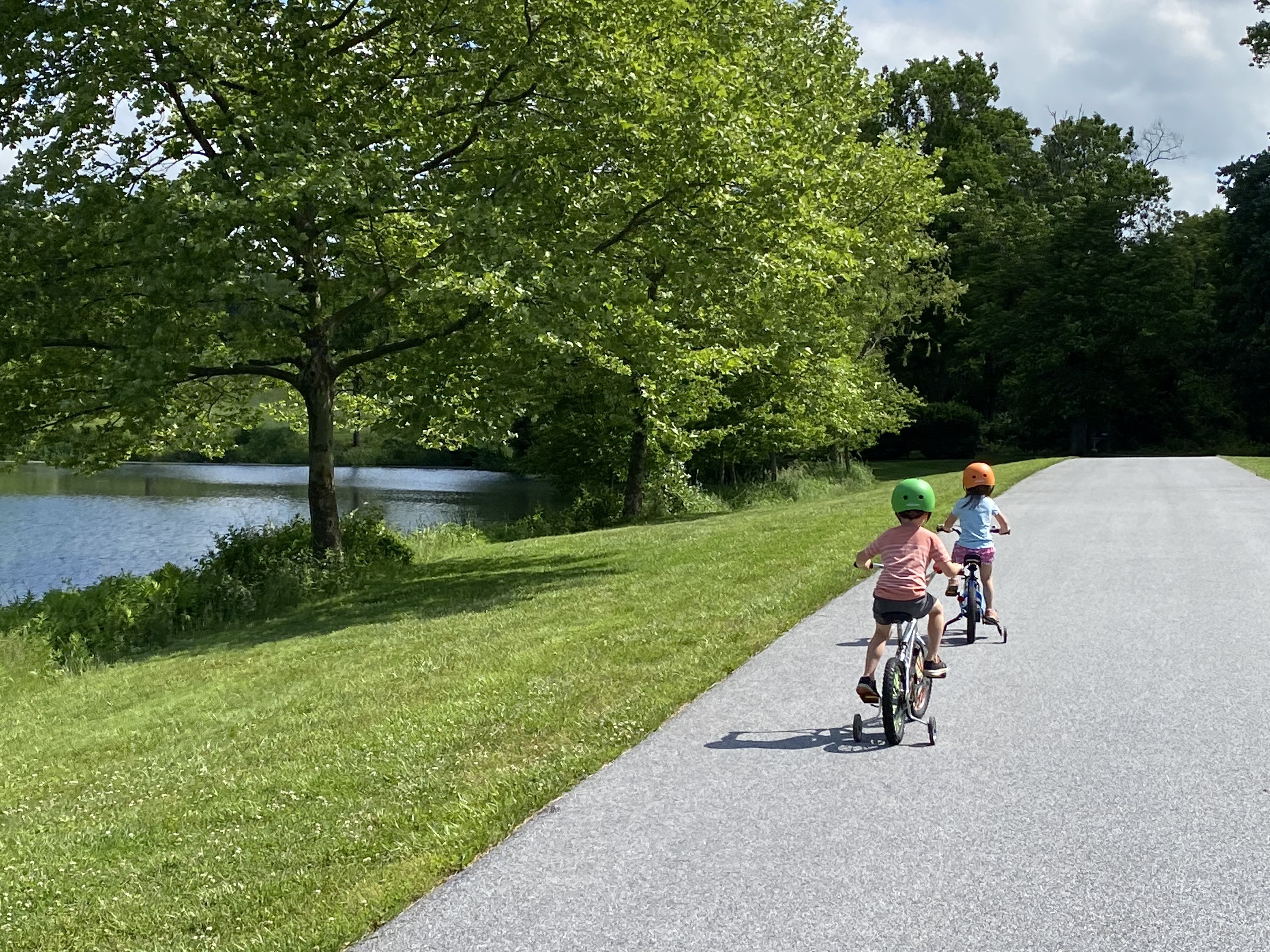 Children biking along the community trail next to the pond